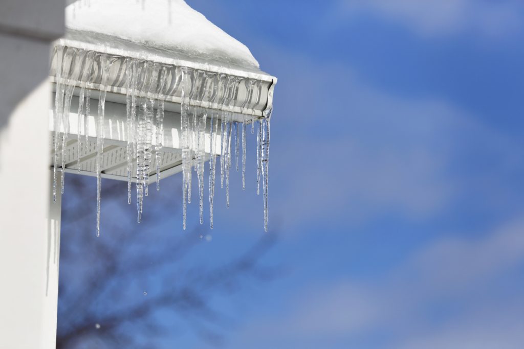 Icicles Melting Over Roof Edge Gutter